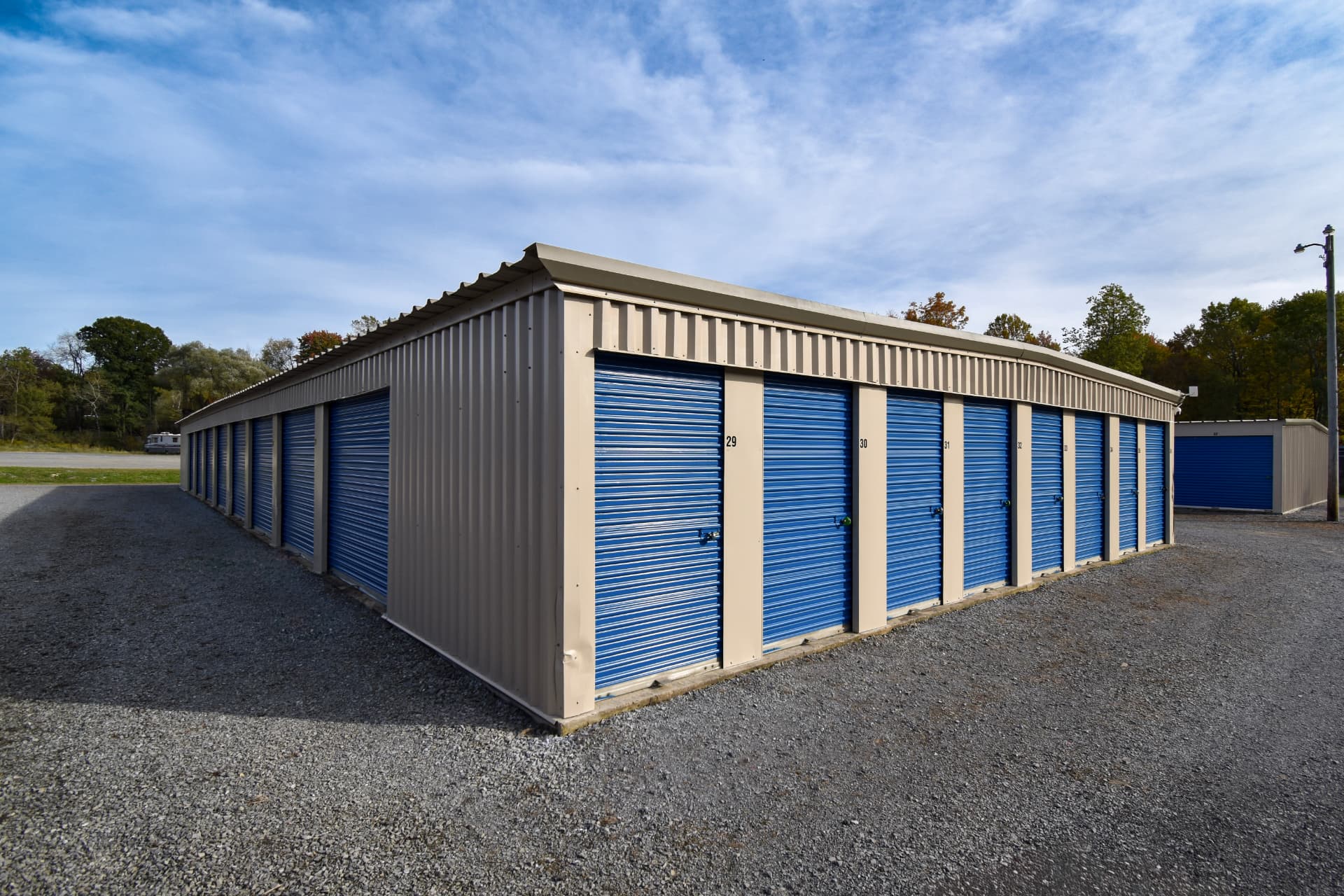 After: the same storage building with blue doors and cleared gravel around it.