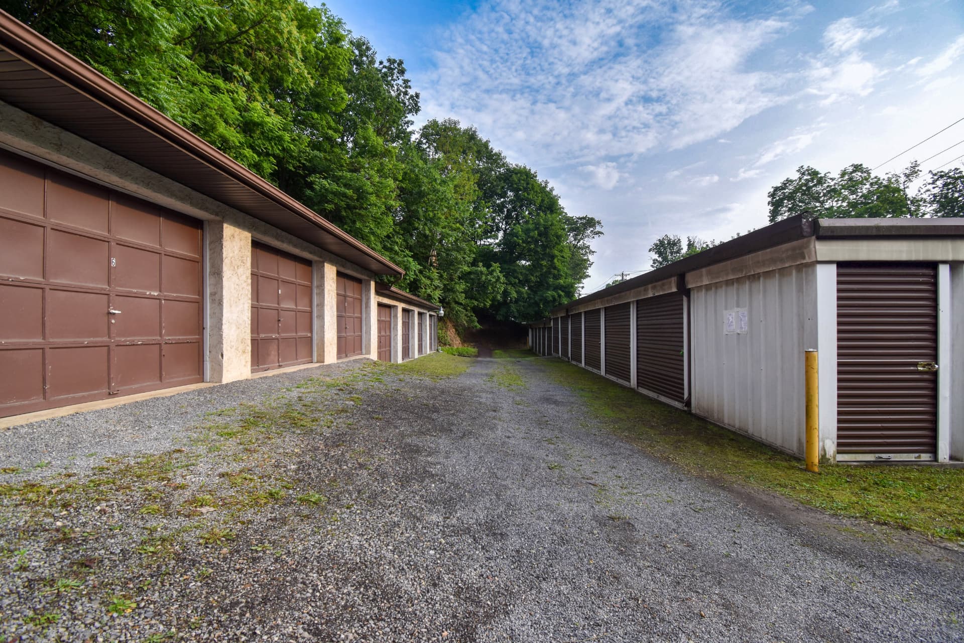 Before: a storage drive with brown doors on one side, weathered metal siding on the other, and weeds growing up through the gravel.
